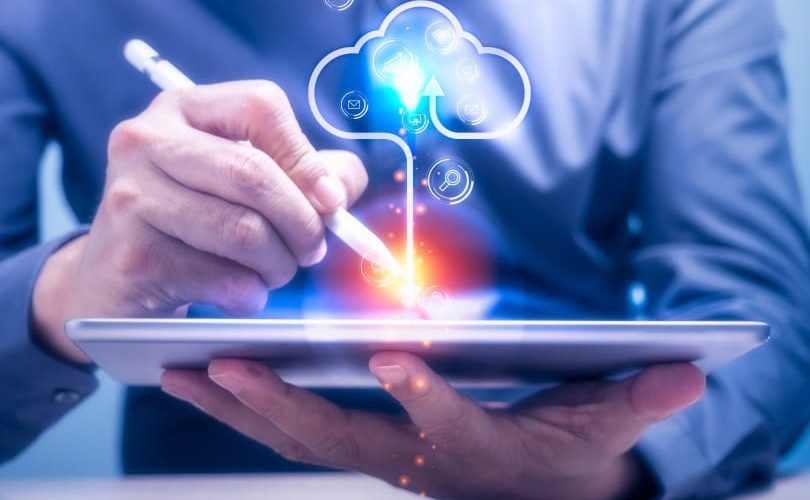 small business cybersecurity through the cloud - man holding tablet with cloud symbol above