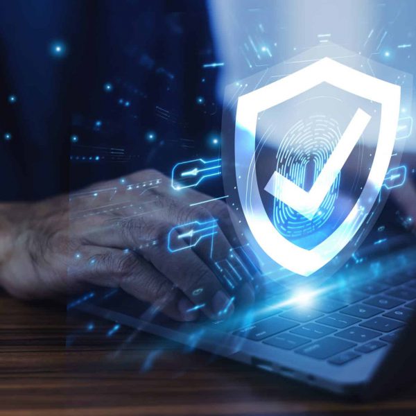 Man working on a laptop with advanced cyber security shield, ensuring the protection of sensitive data and securing the digital environment against potential threats.